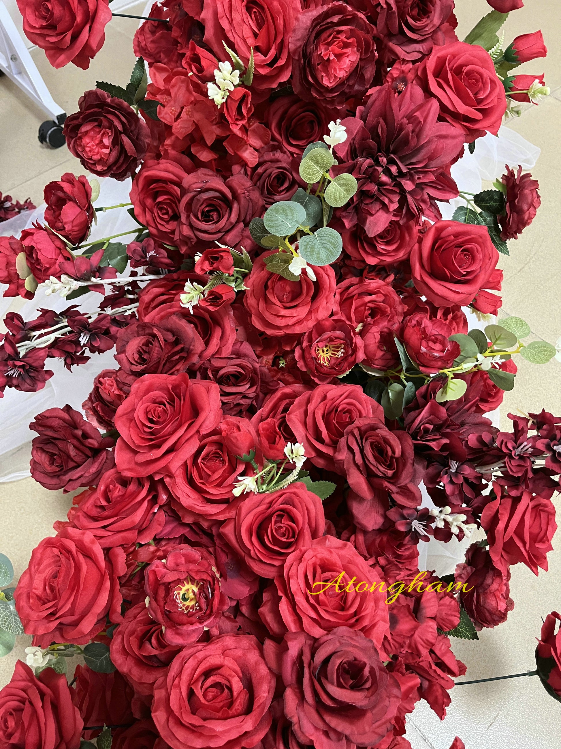 Long burgundy red floral arrangement for reception table decoration